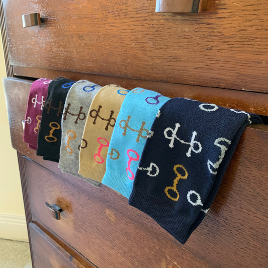 Socks in Maroon Black Grey Tan Aqua and Navy Hanging Over Dresser Drawer with Multi-Color Snaffle Bits in White Brown Gold Blue and Pink