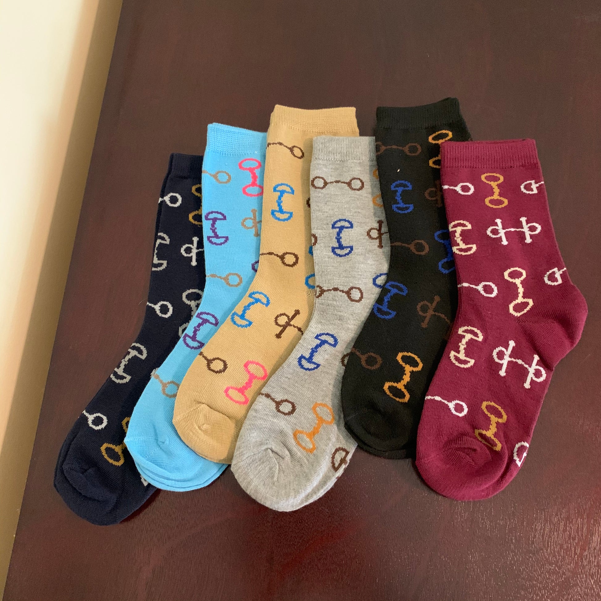 Socks in Maroon Black Grey Tan Aqua and Navy Laying Flat with Multi-Color Snaffle Bits in White Brown Gold Blue and Pink